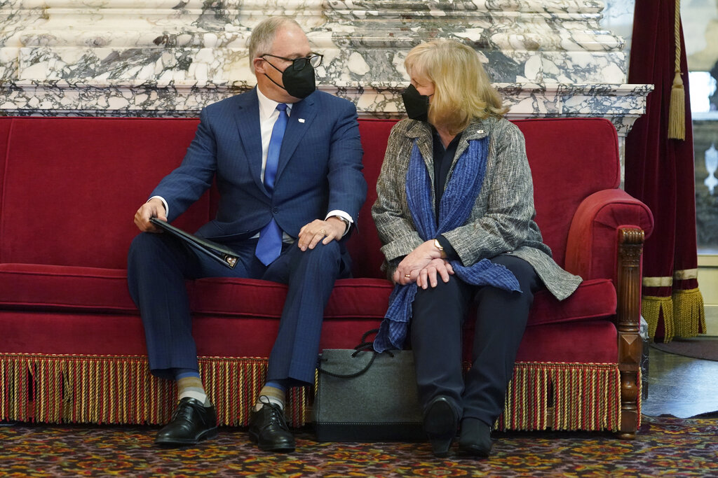 Washington Gov. Jay Inslee holds a copy of his speech as he sits with his wife Trudi before giving his annual State of the State address, Tuesday, Jan. 11, 2022, at the Capitol in Olympia, Wash. Due to cautions against COVID-19, Inslee gave his speech in the State Reception Room and it was shown by streaming video to lawmakers meeting remotely. (AP Photo/Ted S.