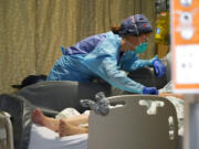 Registered nurse Estella Wilmarth tends to a patient in the acute care unit of Harborview Medical Center, Friday, Jan. 14, 2022, in Seattle.