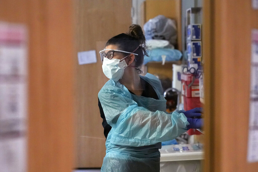 Registered nurse Jessalynn Dest looks across the room while treating a COVID-19 patient in the acute care unit of Harborview Medical Center, Friday, Jan. 14, 2022, in Seattle. Washington Gov. Jay Inslee is deploying 100 members of the state National Guard to hospitals across the state amid staff shortages due to an omicron-fueled spike in COVID-19 hospitalizations. Inslee announced Thursday that teams will be deployed to assist four overcrowded emergency departments at hospitals in Everett, Yakima, Wenatchee and Spokane, and that testing teams will be based at hospitals in Olympia, Richland, Seattle and Tacoma.