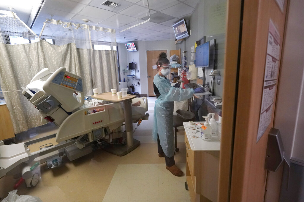 Registered nurse Jessalynn Dest fills out records while treating a COVID-19 patient in the acute care unit of Harborview Medical Center, Friday, Jan. 14, 2022, in Seattle. Washington Gov. Jay Inslee is deploying 100 members of the state National Guard to hospitals across the state amid staff shortages due to an omicron-fueled spike in COVID-19 hospitalizations. Inslee announced Thursday that teams will be deployed to assist four overcrowded emergency departments at hospitals in Everett, Yakima, Wenatchee and Spokane, and that testing teams will be based at hospitals in Olympia, Richland, Seattle and Tacoma.