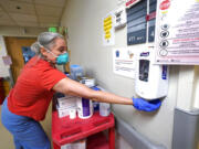 Dr. Alexandra Moretti Morrison cleans her hands after treating a patient in the acute care unit, where about half the patients are COVID-19 positive or in quarantine after exposure, of Harborview Medical Center, Friday, Jan. 14, 2022, in Seattle. Washington Gov. Jay Inslee is deploying 100 members of the state National Guard to hospitals across the state amid staff shortages due to an omicron-fueled spike in COVID-19 hospitalizations. Inslee announced Thursday that teams will be deployed to assist four overcrowded emergency departments at hospitals in Everett, Yakima, Wenatchee and Spokane, and that testing teams will be based at hospitals in Olympia, Richland, Seattle and Tacoma.