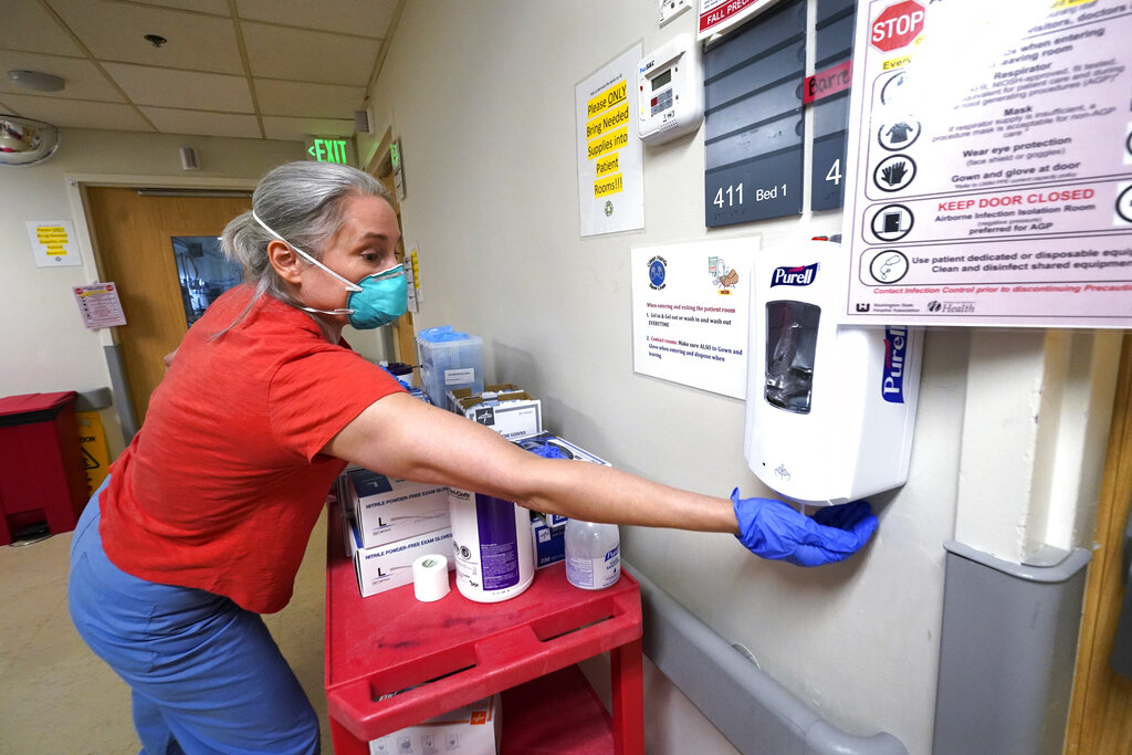 Dr. Alexandra Moretti Morrison cleans her hands after treating a patient in the acute care unit, where about half the patients are COVID-19 positive or in quarantine after exposure, of Harborview Medical Center, Friday, Jan. 14, 2022, in Seattle. Washington Gov. Jay Inslee is deploying 100 members of the state National Guard to hospitals across the state amid staff shortages due to an omicron-fueled spike in COVID-19 hospitalizations. Inslee announced Thursday that teams will be deployed to assist four overcrowded emergency departments at hospitals in Everett, Yakima, Wenatchee and Spokane, and that testing teams will be based at hospitals in Olympia, Richland, Seattle and Tacoma.