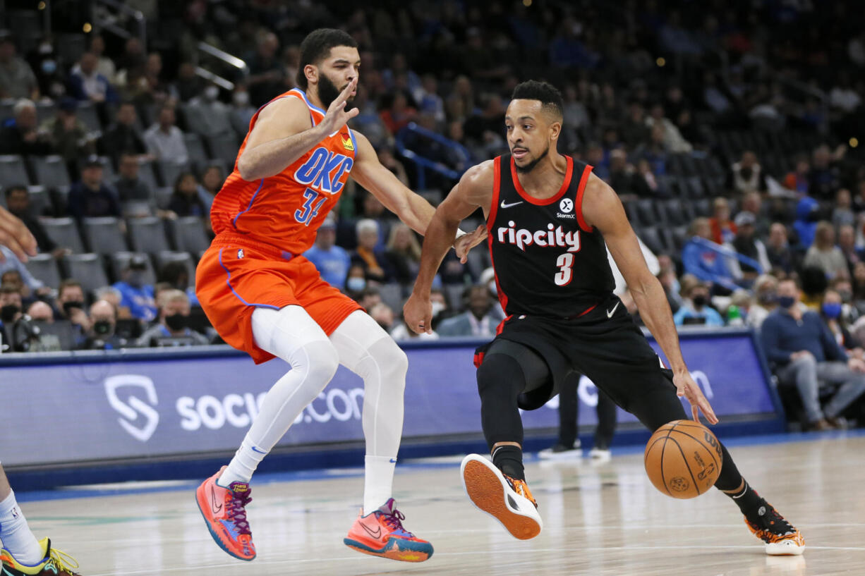 Portland Trail Blazers guard CJ McCollum, right, drives against Oklahoma City Thunder forward Kenrich Williams in the first half of an NBA basketball game Monday, Jan. 31, 2022, in Oklahoma City.