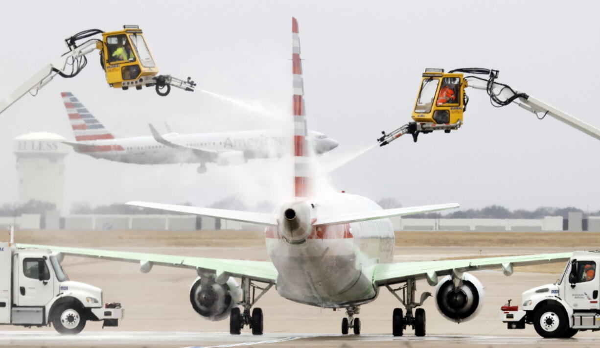 Aerial crews deice an American Airlines jet before it can take off as another lands at Dallas/Fort Worth International Airport, Wednesday, Feb. 23, 2022, in Dallas. Light precipitation was falling as temperatures were in the mid 20's.