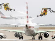 Aerial crews deice an American Airlines jet before it can take off as another lands at Dallas/Fort Worth International Airport, Wednesday, Feb. 23, 2022, in Dallas. Light precipitation was falling as temperatures were in the mid 20's.