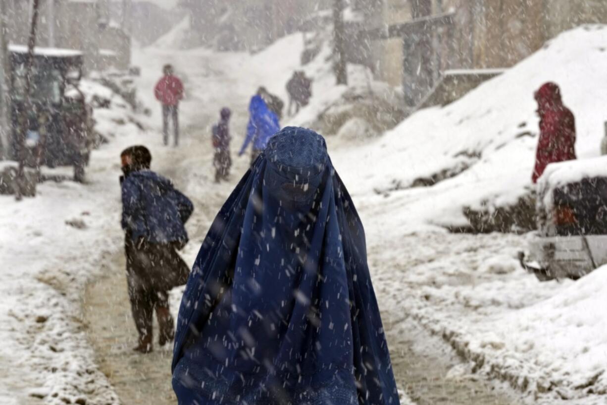 People navigate a snow covered street on a hilltop in Kabul, Afghanistan, Tuesday, Feb. 22, 2022.