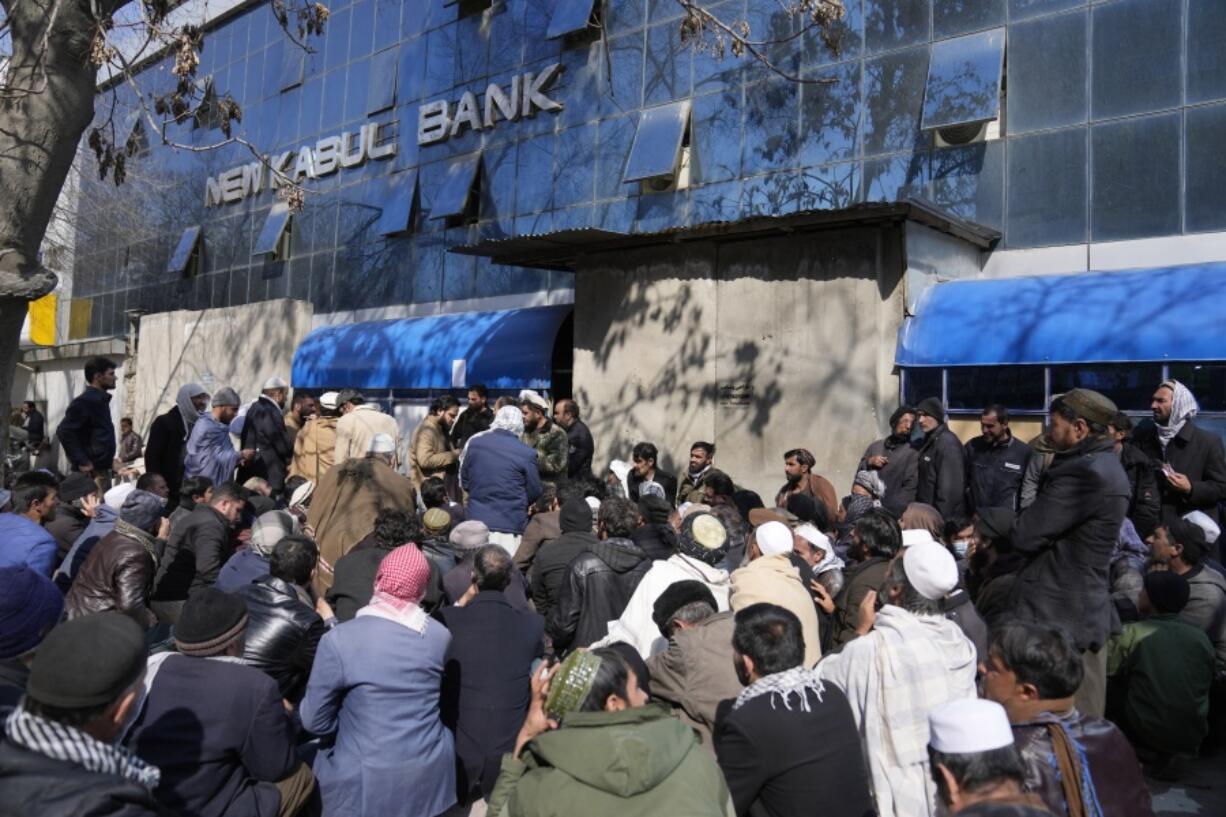 Afghan wait to enter a bank, in Kabul, Afghanistan, Sunday, Feb. 13, 2022. Six months since Kabul was ceded to the Taliban with the sudden and secret departure of U.S.-backed president residents say a calm has settled on the country, but the future is uncertain as the economy teeters on the verge of an economic collapse and the new Taliban rulers tackle the transition from war to relative peace.