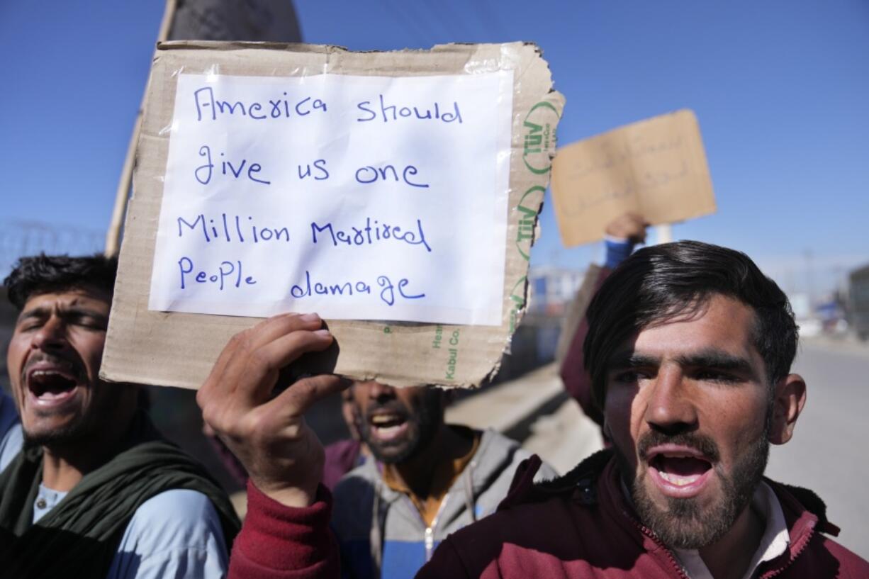 Afghan protesters hold placards and shout slogans against U.S. during a protest condemning President Joe Biden's decision, in Kabul, Afghanistan, Saturday, Feb. 12, 2022. President Biden signed an executive order, Friday, Feb. 11, 2022, to create a pathway to split $7 billion in Afghan assets frozen in the U.S. to fund humanitarian relief in Afghanistan and to create a trust fund to compensate Sept. 11 victims.