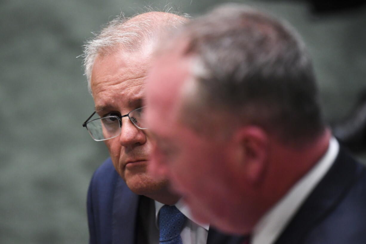 Australian Prime Minister Scott Morrison, rear, listens to Australian Deputy Prime Minister Barnaby Joyce speaking to a statement of acknowledgment of harassment in the workplace of Commonwealth Parliament by the Speaker in the House of Representatives at Parliament House in Canberra, Tuesday, Feb. 8, 2022. Australian political leaders on Tuesday apologized to staffers who have endured decades of bullying, harassment and sexual assault inside Parliamentary House and other government offices.