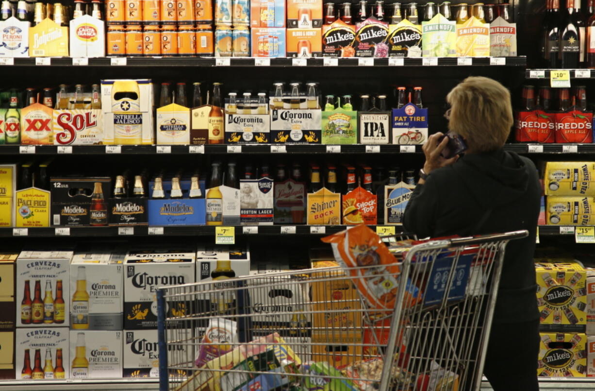 FILE - In this Oct. 1, 2018, photo, a customer looks over the beer selection at Crest Foods in Oklahoma City. In an effort to give smaller breweries a better chance at competing, the Treasury Department this month issued a report full of ideas on how to create a more competitive beer, wine and liquor market. It enlisted the help of state and federal law enforcement agencies for ideas on how to level the playing field.