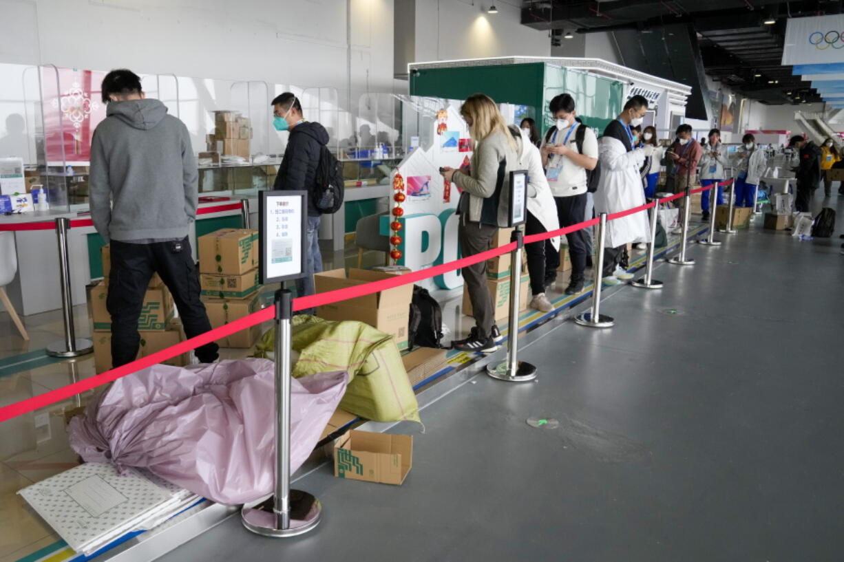 People queue with their parcels outside the post office at the Main Press Center at the 2022 Winter Olympics, Friday, Feb. 11, 2022, in Beijing.