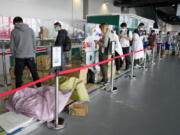 People queue with their parcels outside the post office at the Main Press Center at the 2022 Winter Olympics, Friday, Feb. 11, 2022, in Beijing.