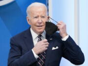 President Joe Biden removes his face mask to speak in the South Court Auditorium in the Eisenhower Executive Office Building on the White House complex, Tuesday, Feb. 22, 2022, in Washington.