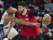 Milwaukee Bucks forward Giannis Antetokounmpo, left, reaches for the ball dribbled by Portland Trail Blazers center Jusuf Nurkic during the first half of an NBA basketball game in Portland, Ore., Saturday, Feb. 5, 2022.