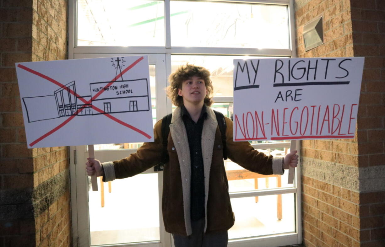 Huntington High School senior Max Nibert holds signs he plans to use during a student walkout at the school in Huntington, W.Va. on Wednesday, Feb. 9, 2022. The protest follows an evangelistic Christian revival assembly last week that some students at Huntington High were mandated by teachers to attend - a violation of students' civil rights, Nibert says. (AP Photo/Leah M.