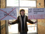 Huntington High School senior Max Nibert holds signs he plans to use during a student walkout at the school in Huntington, W.Va. on Wednesday, Feb. 9, 2022. The protest follows an evangelistic Christian revival assembly last week that some students at Huntington High were mandated by teachers to attend - a violation of students' civil rights, Nibert says. (AP Photo/Leah M.