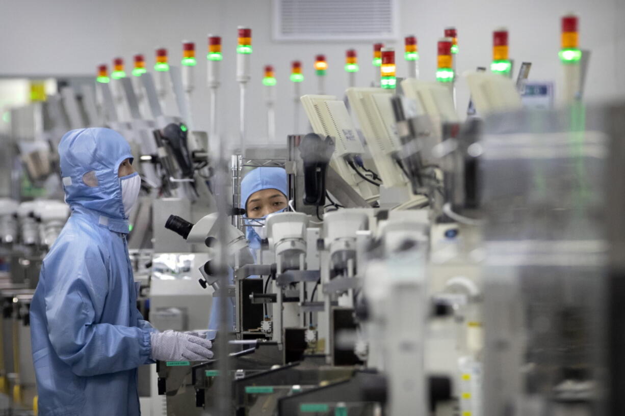 FILE - Employees wearing protective equipment work at a semiconductor production facility for Renesas Electronics during a government organized tour for journalists in Beijing, on May 14, 2020. House Democrats are poised to approve legislation Friday, Feb. 4, 2022, that they say positions the United States to better compete with China economically and on the global stage by strengthening the domestic semiconductor industry, shoring up strained supply chains and bolstering international alliances.