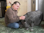 Wyverne Flatt who is fighting to keep his pot-bellied pig Ellie as an emotional support animal poses for a photograph at his home Wednesday, Feb. 2, 2022, in Canajoharie, N.Y. Village officials consider Ellie a farm animal, and not allowed in the village.