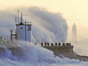 Waves crash against the sea wall and Porthcawl Lighthouse in Porthcawl, Bridgend, Wales,, Britain, as Storm Eunice makes landfall Friday, Feb. 18, 2022. Millions of Britons are being urged to cancel travel plans and stay indoors Friday amid fears of high winds and flying debris as the second major storm this week prompted a rare "red" weather warning across southern England.