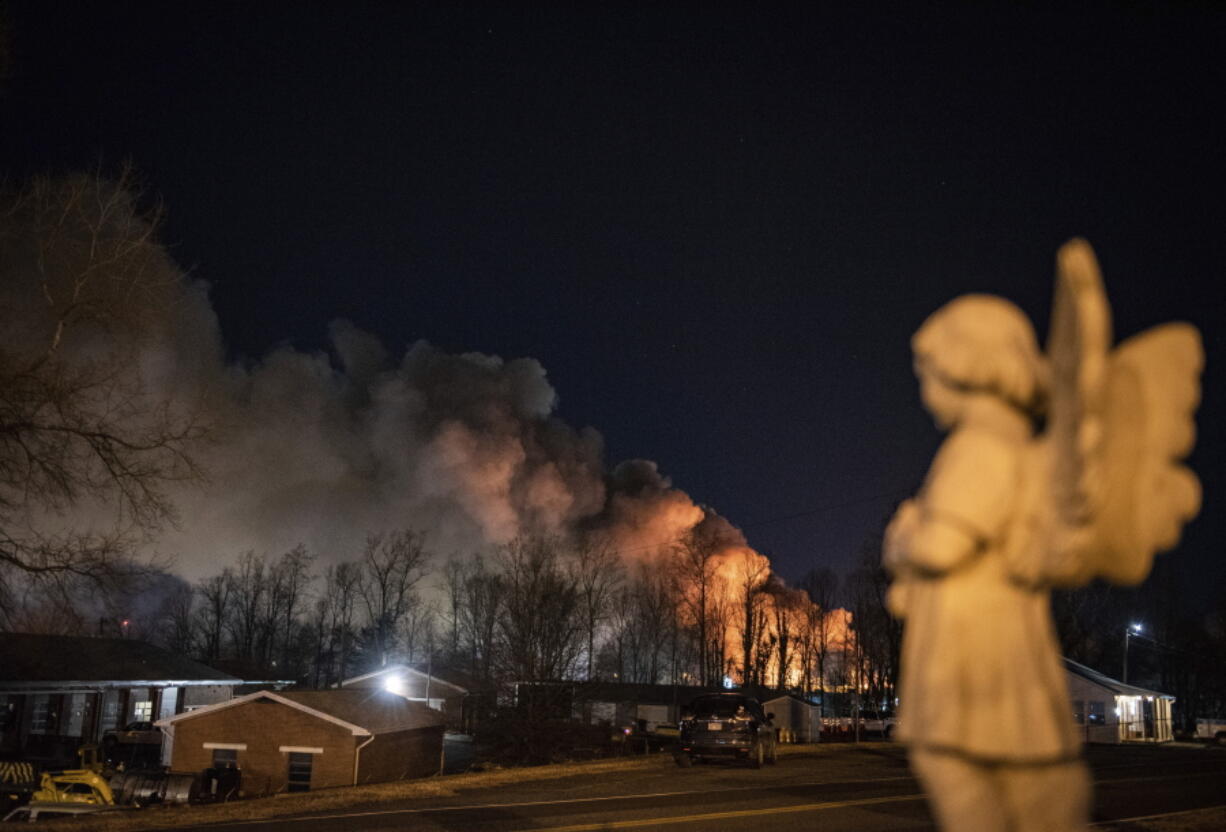 An angel statue faces in the direction of billowing smoke from a fire at the Weaver Fertilizer Plant on Monday, Jan. 31, 2022, in Winston-Salem, N.C.