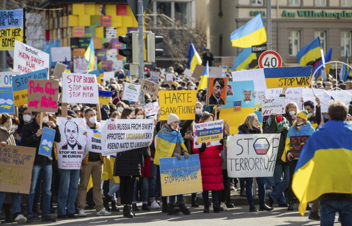 Numerous people demonstrate with signs and flags on Wilhelmsplatz in Stuttgart, Germany, against Russia's military deployment in Ukraine on Saturday, Feb. 26, 2022.