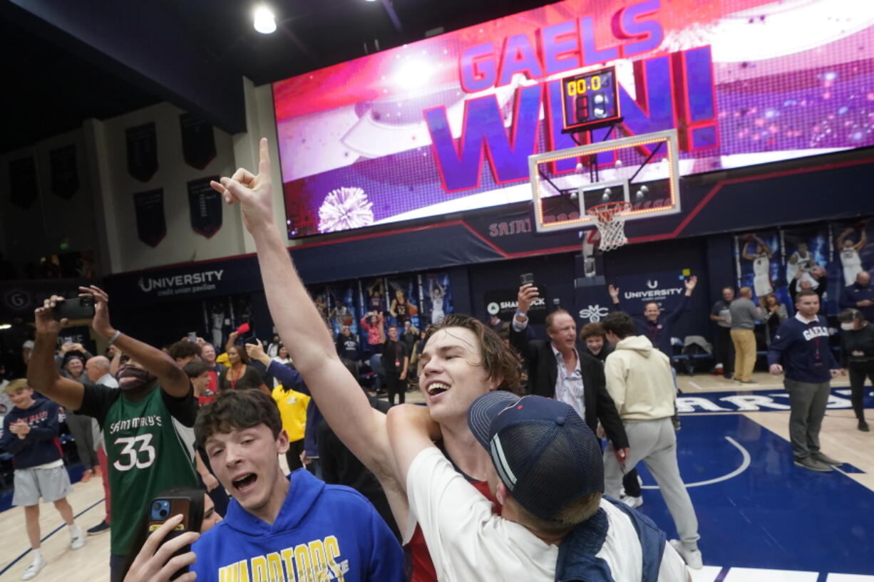 Saint Mary's guard Alex Ducas, middle, celebrates with fans after Saint Mary's defeated Gonzaga in an NCAA college basketball game in Moraga, Calif., Saturday, Feb. 26, 2022.