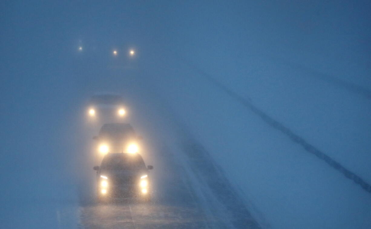 FILE - Headlights from morning commuters can be seen through blowing snow as they make their way along Highway 441, on Jan. 28, 2019, in Appleton, Wis. Anyone who has ever been temporarily blinded by high-beam headlights from an oncoming car will be happy to hear this. U.S. regulators are about to allow new high-tech headlights that can automatically tailor beams so they focus on dark areas of the road and don't create glare for oncoming drivers.