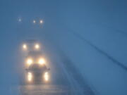 FILE - Headlights from morning commuters can be seen through blowing snow as they make their way along Highway 441, on Jan. 28, 2019, in Appleton, Wis. Anyone who has ever been temporarily blinded by high-beam headlights from an oncoming car will be happy to hear this. U.S. regulators are about to allow new high-tech headlights that can automatically tailor beams so they focus on dark areas of the road and don't create glare for oncoming drivers.