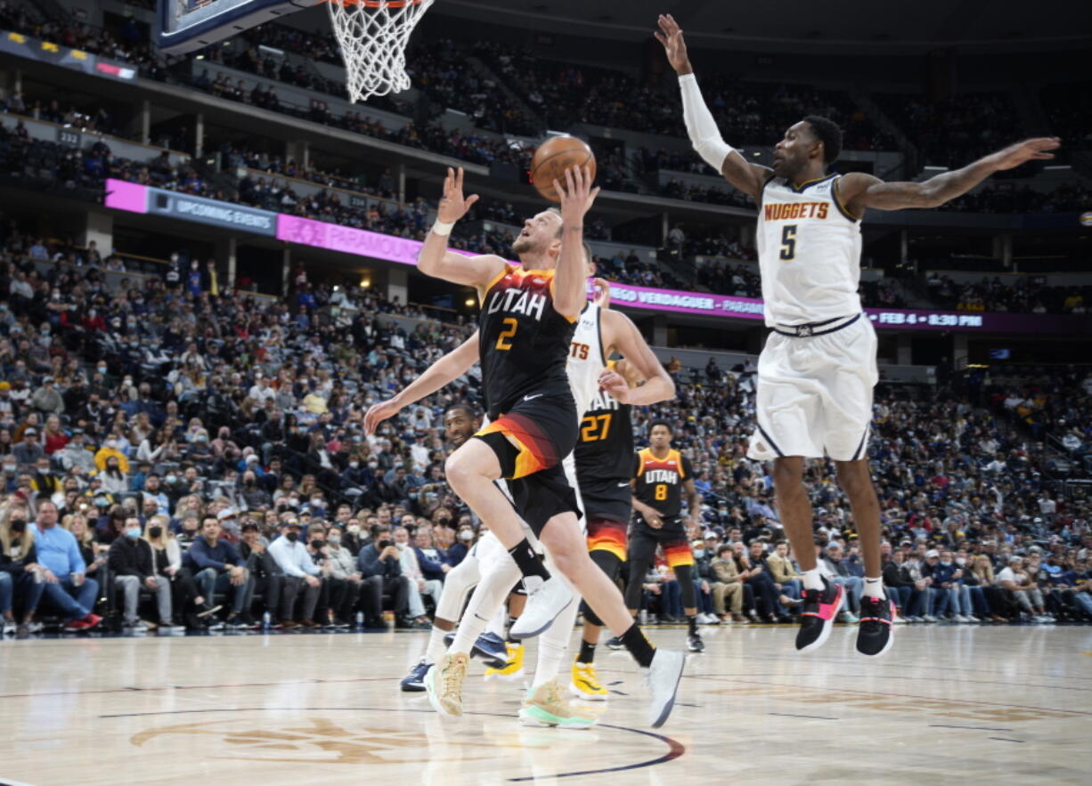 Utah Jazz guard Joe Ingles, left, drives the lane past Denver Nuggets forward Will Barton in the second half of an NBA basketball game Sunday, Jan. 16, 2022, in Denver.