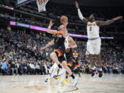 Utah Jazz guard Joe Ingles, left, drives the lane past Denver Nuggets forward Will Barton in the second half of an NBA basketball game Sunday, Jan. 16, 2022, in Denver.