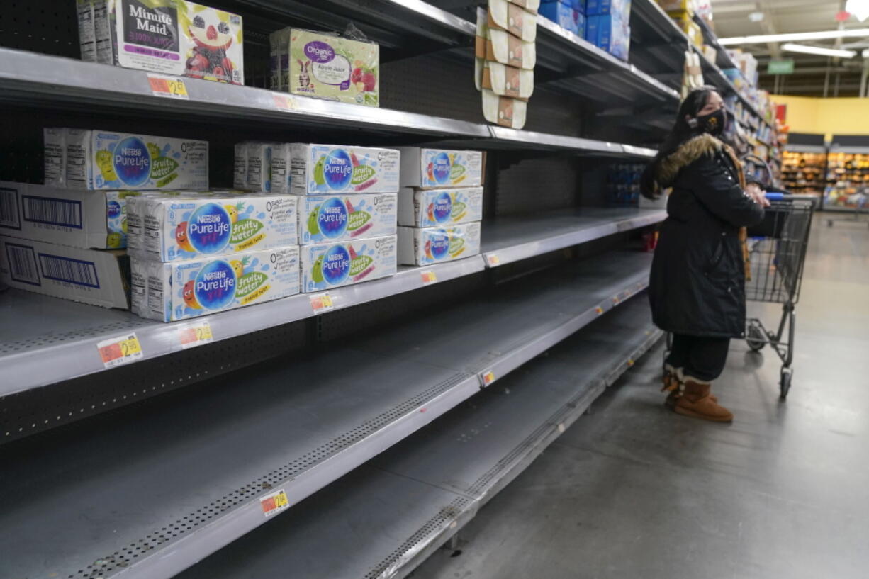 FILE - A woman looks over shelves, some of which are empty, at a Walmart store in Teterboro, N.J., on Jan. 12, 2022. The Justice Department is launching a new initiative aimed at identifying companies that exploit supply chain disruptions in the U.S. to make increased profits in violation of federal antitrust laws.