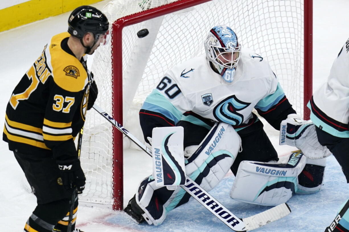 Seattle Kraken goaltender Chris Driedger (60) looks for the shot as the puck sails over his shoulder for a goal by Boston Bruins right wing David Pastrnak during the second period of an NHL hockey game, Tuesday, Feb. 1, 2022, in Boston. At left is Boston Bruins center Patrice Bergeron (37).