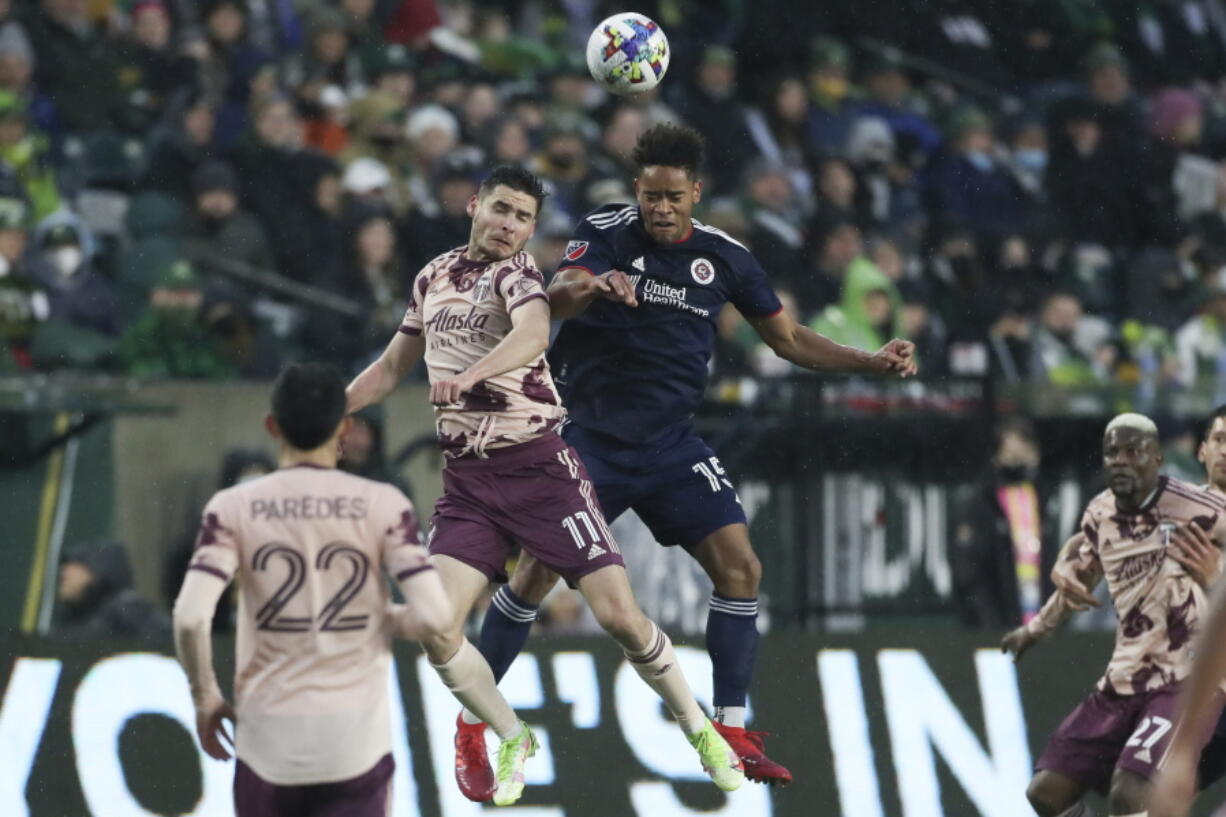 Portland Timbers forward Jaroslaw Niezgoda and New England Revolution defender Brandon Bye jump up to head the ball during the first half of an MLS soccer match, Saturday, Feb. 26, 2022, in Portland, Ore.