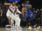 Orlando Magic guard Gary Harris,right, looks to pass the ball as Portland Trail Blazers forward Trendon Watford, left, defends during the first half of an NBA basketball game in Portland, Ore., Tuesday, Feb. 8, 2022.