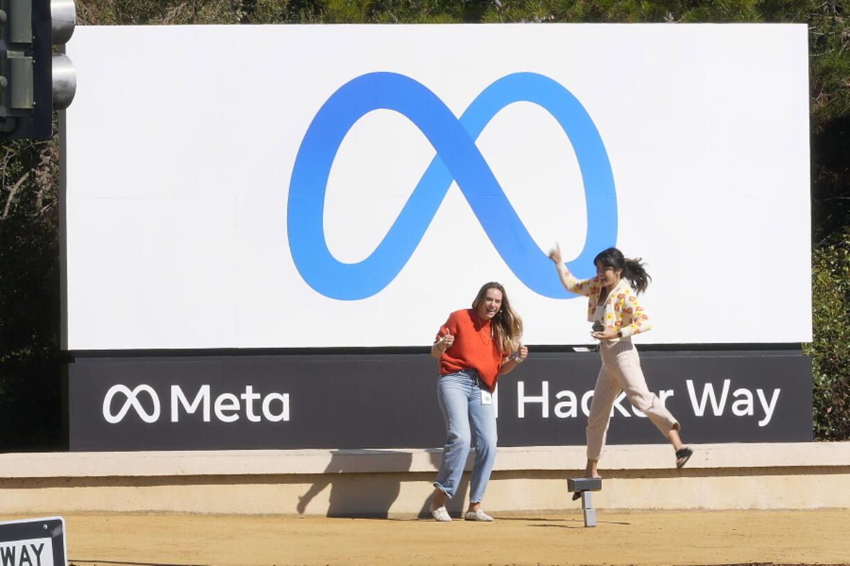 FILE - Facebook employees take a photo with the company's new name and logo outside its headquarters in Menlo Park, Calif., on Oct. 28, 2021.  Meta, the company that owns Facebook, Instagram and WhatsApp, saw its stock plunge after-hours Wednesday, Feb. 2, 2022, after reporting a rare decline in its fourth quarter profit due to a sharp increase in expenses.