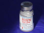 FILE - In this March 4, 2021 file photo, a vial of the Moderna COVID-19 vaccine rests on a table at a drive-up mass vaccination site in Puyallup, Wash., south of Seattle.  Moderna's COVID-19 vaccine brought in nearly $7 billion in the final quarter of 2021, and the drugmaker says it has signed purchase agreements for another $19 billion in sales this year.   (AP Photo/Ted S.