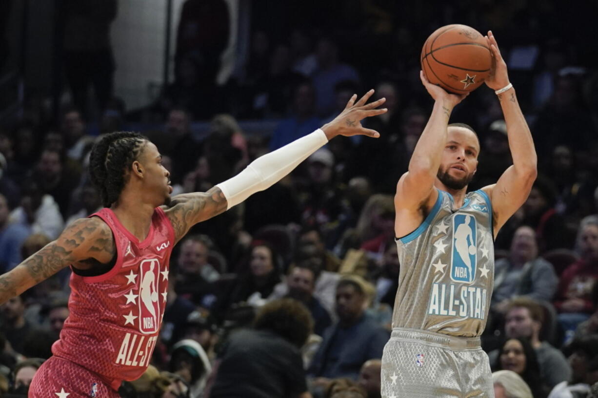 Golden State Warriors' Stephen Curry, right, shoots for three as Memphis Grizzlies' Ja Morant defends during the second half of the NBA All-Star basketball game, Sunday, Feb. 20, 2022, in Cleveland.