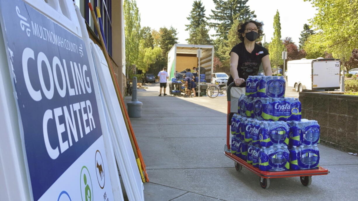 FILE - A volunteer helps set up snacks at a cooling center established to help vulnerable residents ride out a dangerous heat wave on Aug. 11, 2021. The historic heat wave, which toppled all-time temperature records, killed more than 200 people in Oregon and Washington. Now, lawmakers in the Pacific Northwest are eyeing several emergency heat relief bills aimed at helping vulnerable populations. The proposed measures would provide millions in funding for cooling systems and weather shelters during future extreme weather events.