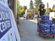 FILE - A volunteer helps set up snacks at a cooling center established to help vulnerable residents ride out a dangerous heat wave on Aug. 11, 2021. The historic heat wave, which toppled all-time temperature records, killed more than 200 people in Oregon and Washington. Now, lawmakers in the Pacific Northwest are eyeing several emergency heat relief bills aimed at helping vulnerable populations. The proposed measures would provide millions in funding for cooling systems and weather shelters during future extreme weather events.