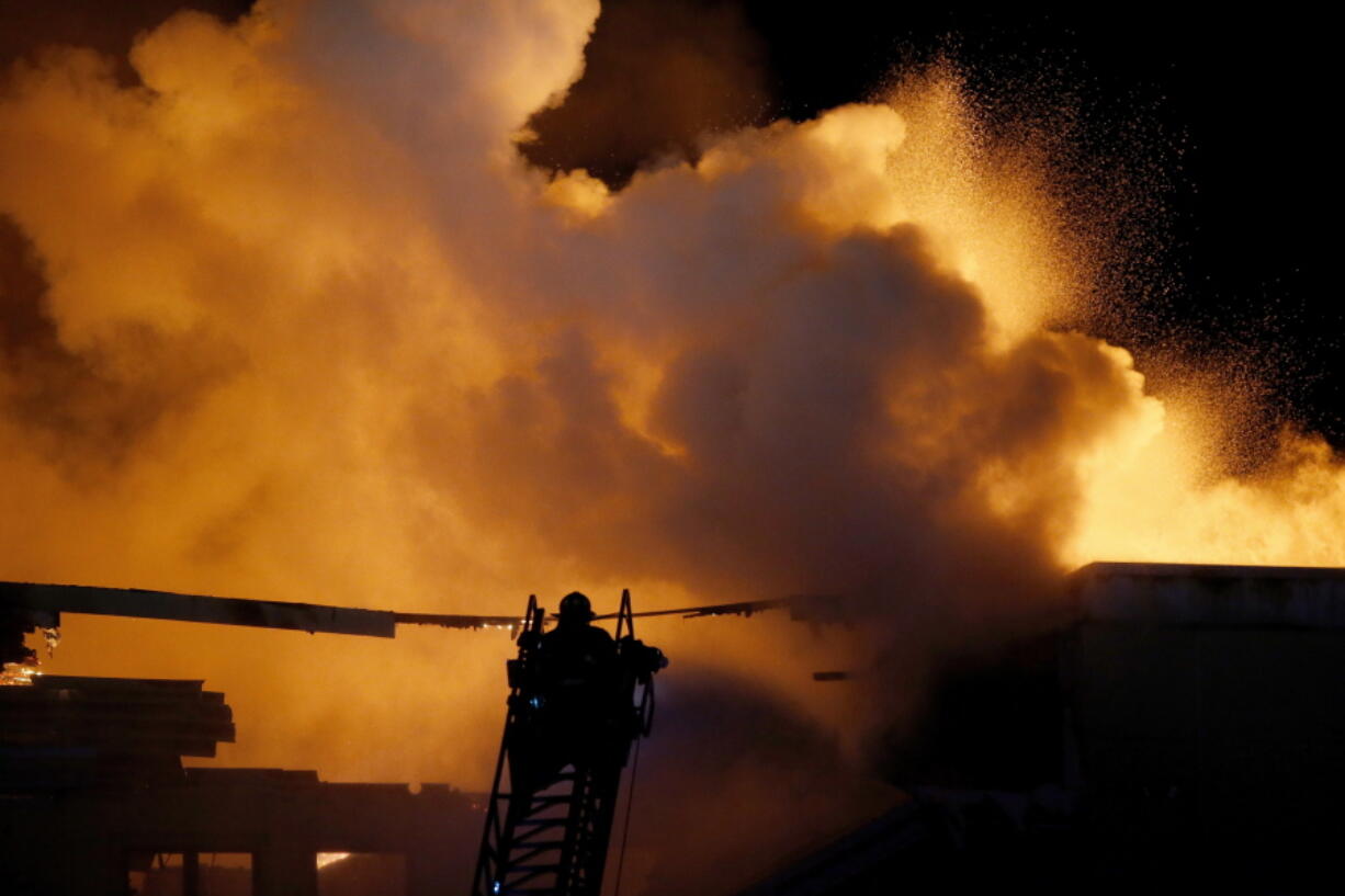 A firefighter battles a large fire in Oklahoma City, Tuesday, Feb., 8, 2022. The massive fire ripped through an empty five-story hotel and apartment complex in northwest Oklahoma City that was under construction, fire officials said.