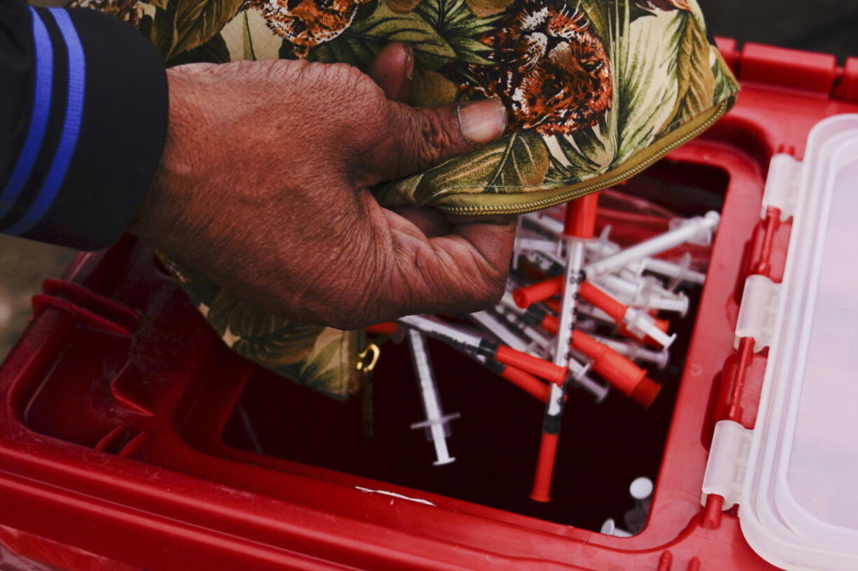 Keith Lewis disposes of used syringes at a needle exchange run by Camden Area Health Education Center in Camden, N.J., Thursday, Feb. 24, 2022.  Four companies involved in the opioid industry are finalizing settlements over the addiction crisis in the U.S. in deals that could total $26 billion over 18 years.