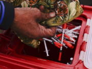 Keith Lewis disposes of used syringes at a needle exchange run by Camden Area Health Education Center in Camden, N.J., Thursday, Feb. 24, 2022.  Four companies involved in the opioid industry are finalizing settlements over the addiction crisis in the U.S. in deals that could total $26 billion over 18 years.