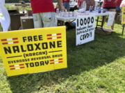 FILE - Signs are displayed at a tent during a health event on June 26, 2021, in Charleston, W.Va. Volunteers at the tent passed free doses of naloxone, a drug that reverses the effects of an opioid overdose by helping the person breathe again. The U.S. needs a more nimble strategy and Cabinet-level leadership to counter its festering opioid epidemic, a bipartisan congressional commission said Tuesday.