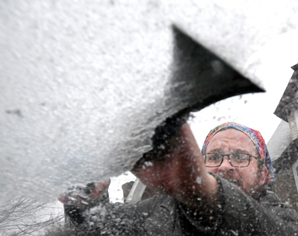 Jason Fried scraps ice off the windshield of his minivan, on Friday, Feb. 25, 2022, in Erie, Pa. "I'm over it," said Fried, 42, of the latest batch of winter weather in the Erie region.