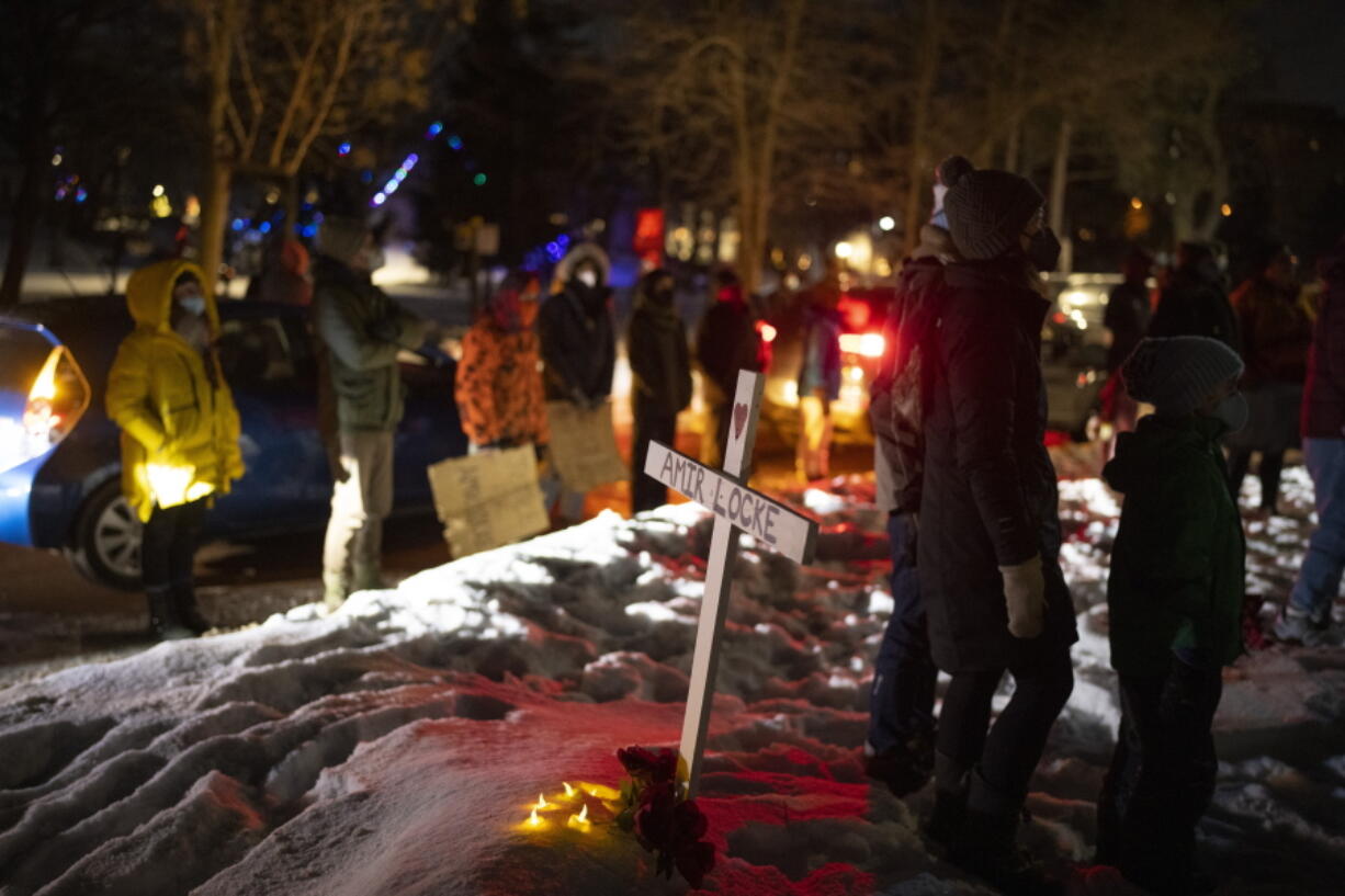 People stand by a cross planted in the boulevard outside homes at the intersection of and Dean Parkway and W. 28th St. in Minneapolis Sunday night, Feb. 6, 2022. At least 150 demonstrators in a caravan of dozens of cars gathered outside a home thought to be where Interim Minneapolis Police Chief Amelia Huffman resides on Dean Parkway to call for justice for Amir Locke, who was shot and killed by Minneapolis Police the previous week.