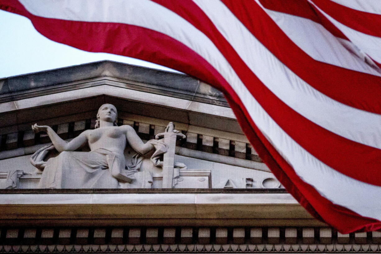 FILE - An American flag flies outside the Department of Justice in Washington, March 22, 2019. The Justice Department says a New York couple was arrested Tuesday on charges of conspiring to launder cryptocurrency that was stolen from a 2016 hack of a virtual currency exchange. Besides the arrests, federal law enforcement officials also revealed that the Justice Department has seized roughly $3.6 billion in cryptocurrency linked to the hack of Bitfinex, a virtual currency exchange whose systems were breached nearly six years ago.