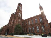 FILE - The Smithsonian Institution's Smithsonian Castle is seen at the National Mall in Washington, Jan. 27, 2015. The Smithsonian will commemorate Women's History Month in March 2022 by displaying 120 3D-printed statues depicting women who have excelled in the fields of science and technology. The life-size neon orange statues will be displayed in the Smithsonian Gardens and in select museums in the Smithsonian network in March.