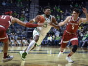 Oregon forward Quincy Guerrier (13) drives to the basket while guarded by Stanford forward Jaiden Delaire (11) and guard Michael O'Connell (5) during the first half of an NCAA college basketball game Thursday, Feb. 10, 2022, in Eugene, Ore.