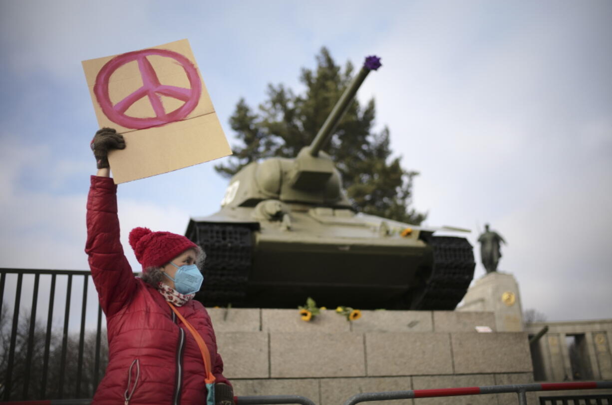 A woman shows a peace sign in front of a Russian WWII tank at the Soviet War Memorial at the bolevard 'Strasse des 17. Juni' alongside a rally against Russia's invasion of Ukraine in Berlin, Germany, Sunday, Feb. 27, 2022.