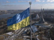 A view of Ukraine's national flag waves above the capital with the Motherland Monument on the right, in Kyiv Sunday, Feb. 13, 2022. Some airlines have halted or diverted flights to Ukraine amid heightened fears that an invasion by Russia is imminent despite intensive weekend talks between the Kremlin and the West.